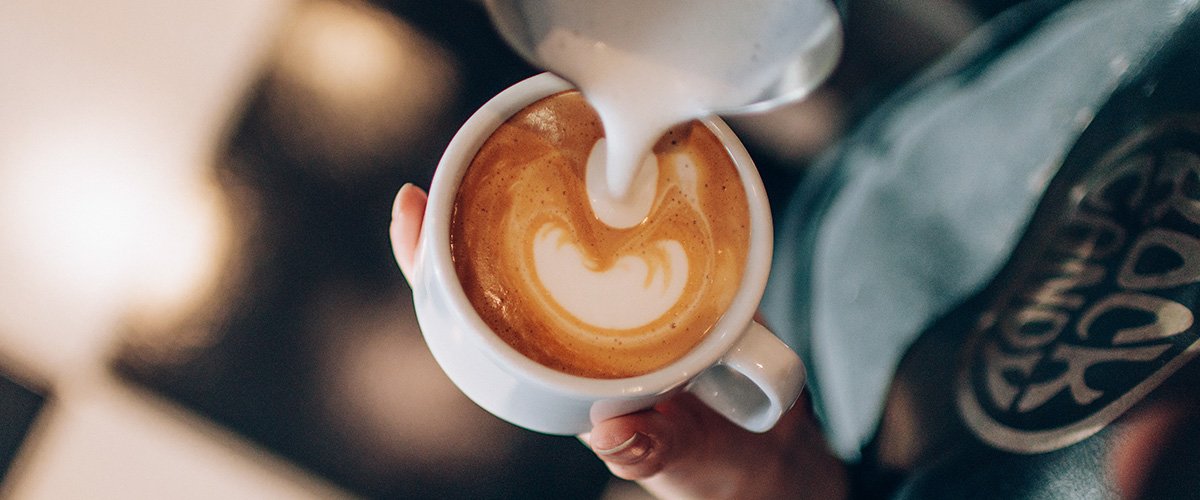 barista preparando latte art com leite vaporizado em xícara café