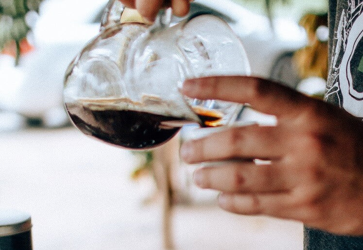 Homem com jarra de vidro servindo café