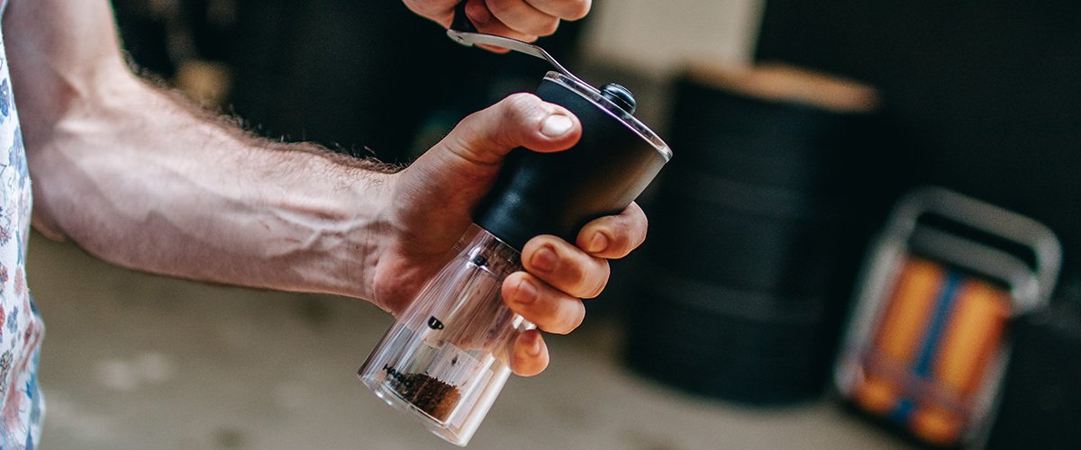 homem moendo café em moedor manual