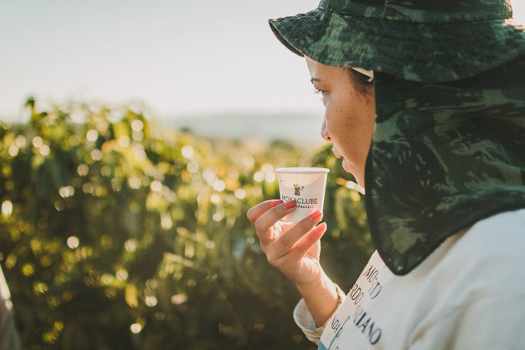 mulher tomando café olhando para plantação