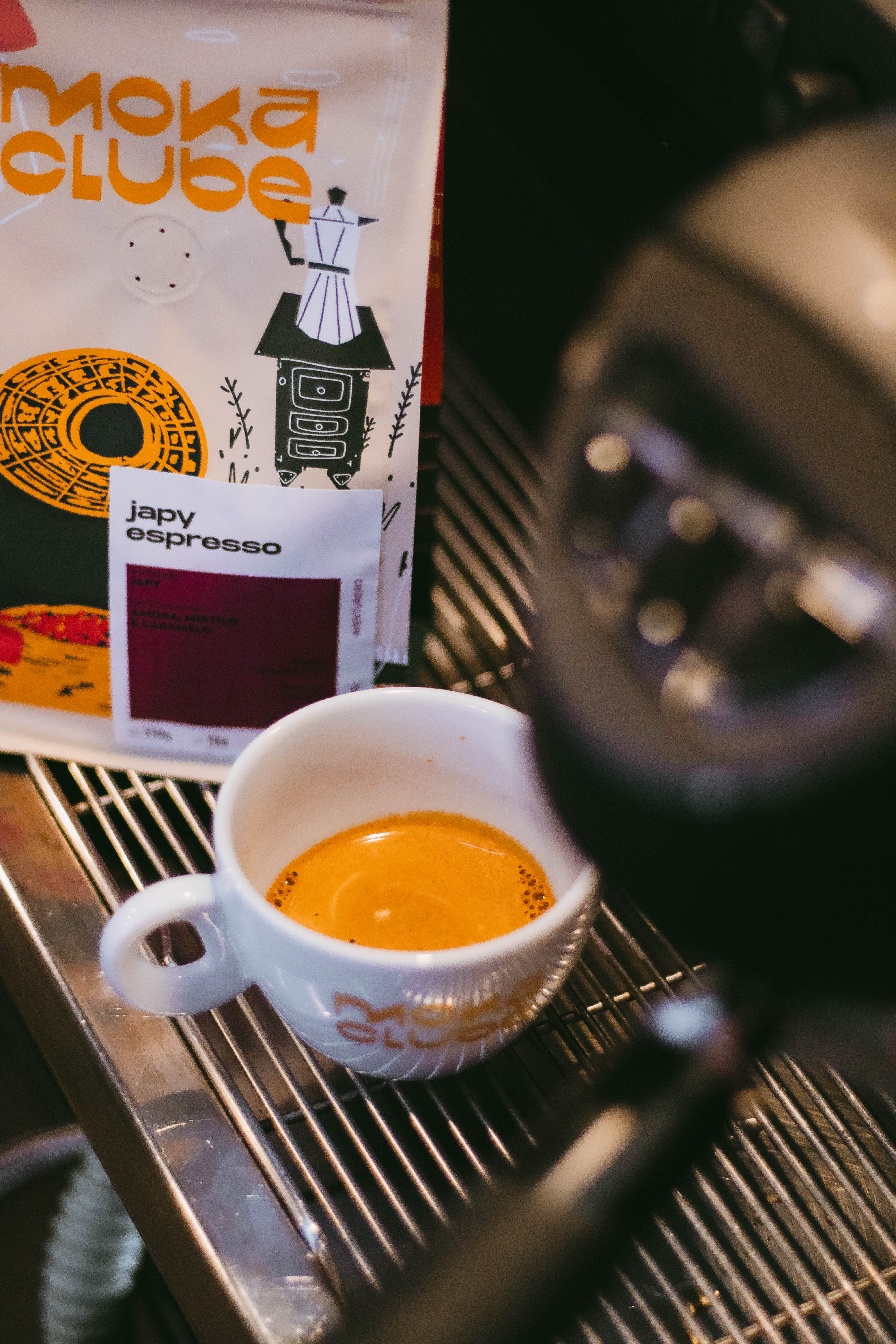 Xícara de café e pacote em cima de máquina de espresso