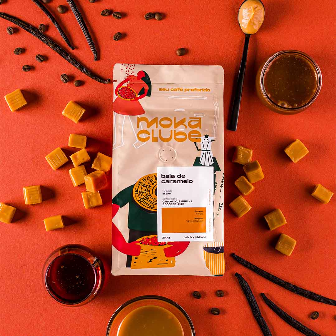 Pacote de 250g de café bala de caramelo, em sua volta muitas balas de caramelo espalhadas e copos de café