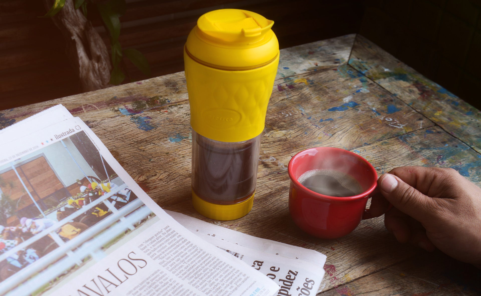 Pressca amarela ao lado do jornal e de uma xícara de café