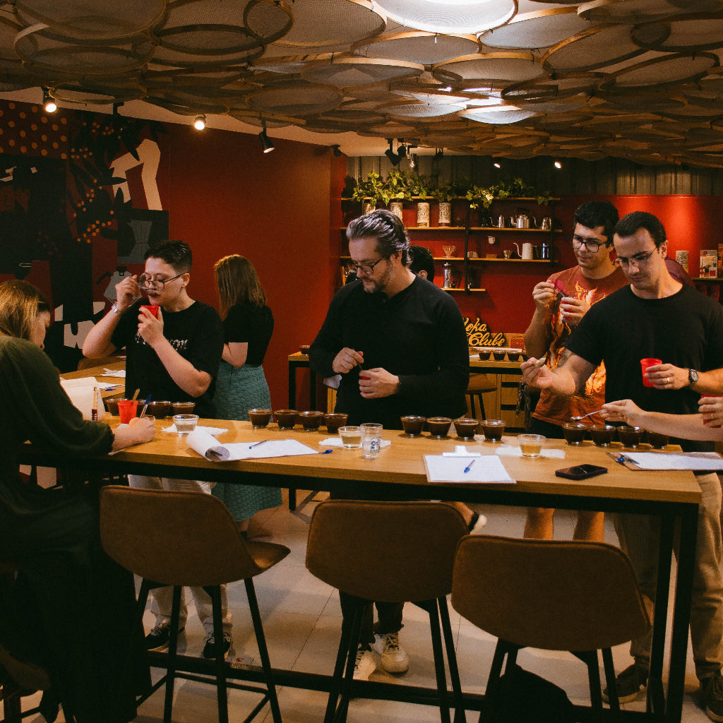 Pessoas provando cafés ao redor de mesa de madeira