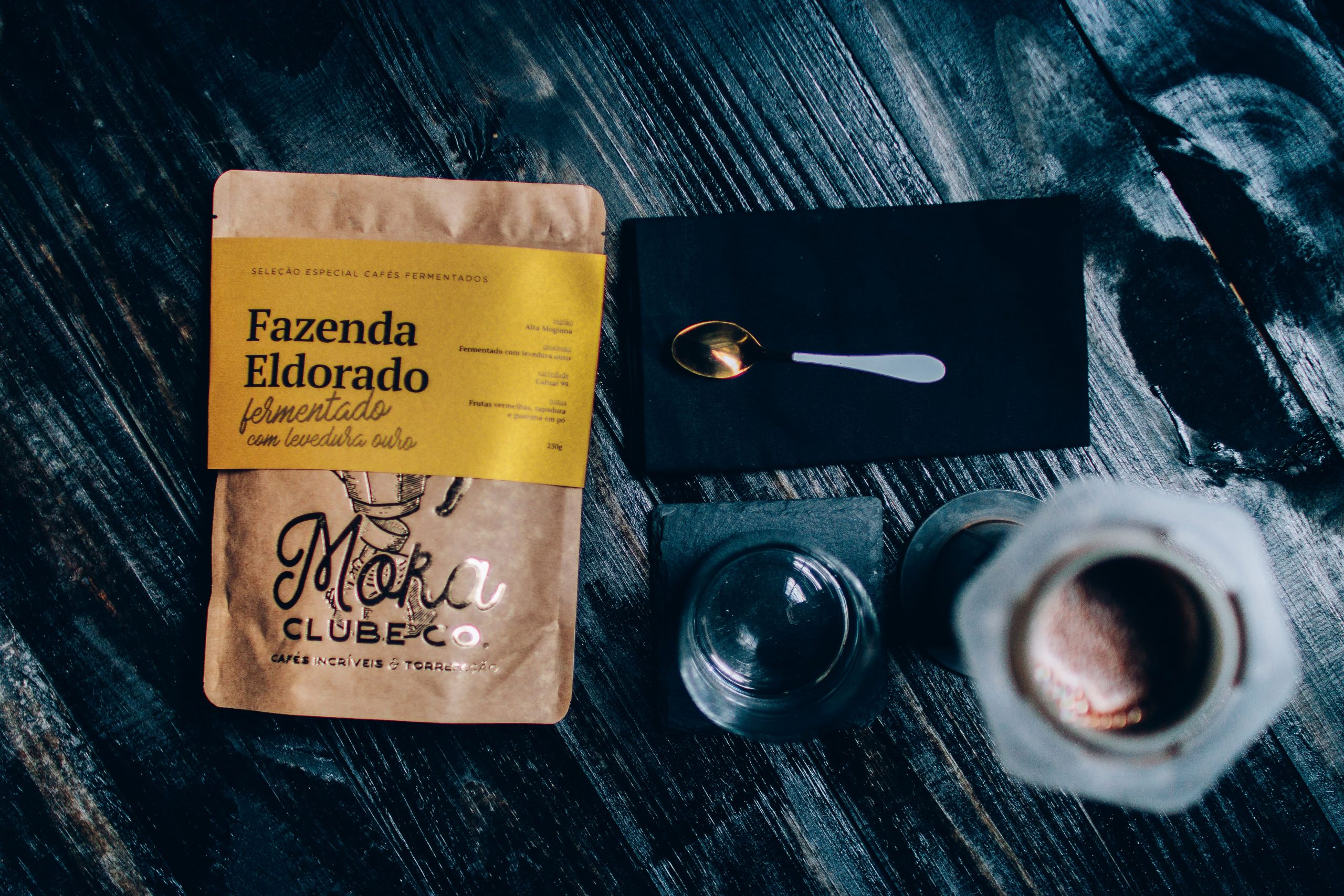 Tipo de grão de café da Fazenda Eldorado disponível no Moka. Rótulo amarelo e, ao lado, uma colher.