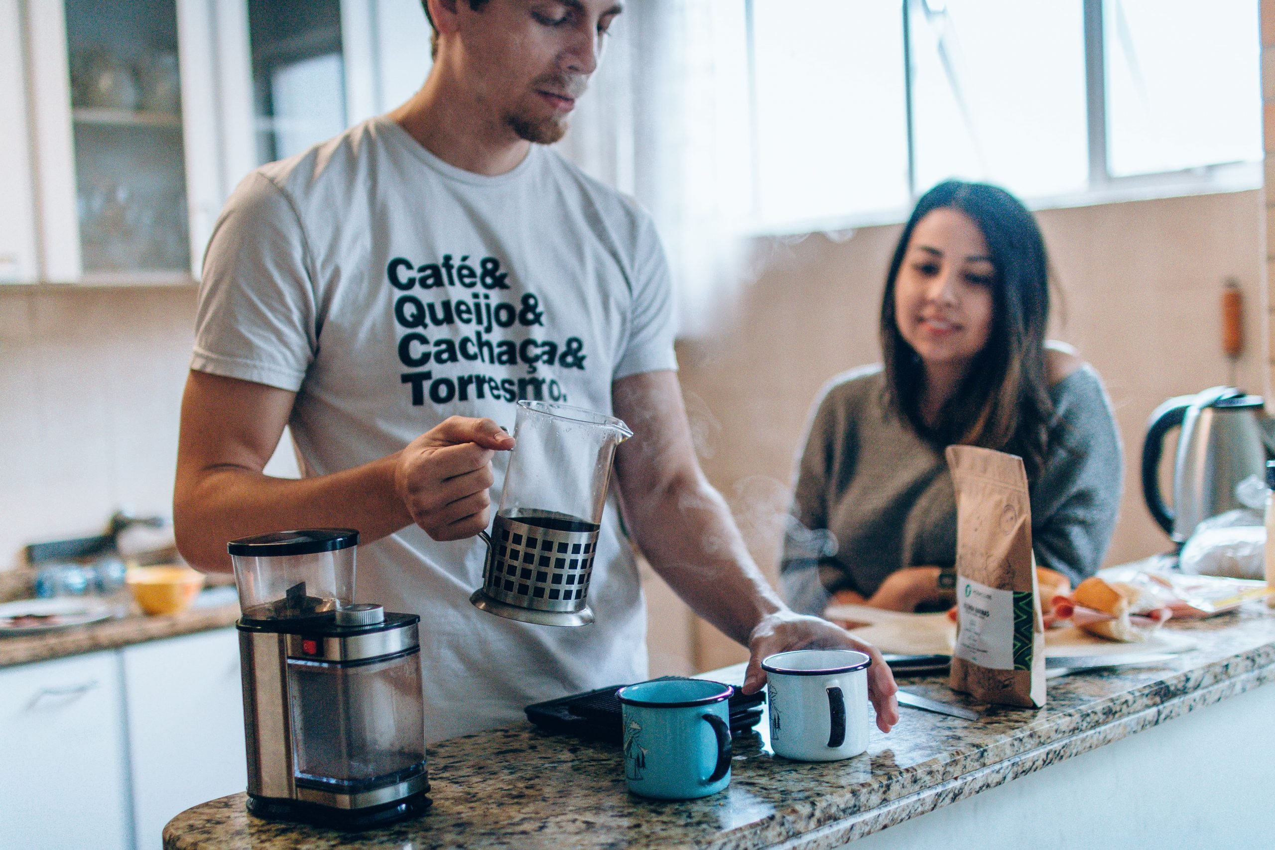 Homem e mulher na cozinha, preparando um café com o grão especial do Moka em uma prensa francesa.