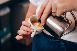 Mulher fazendo art latte no café.