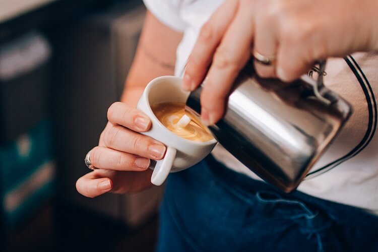 Mulher fazendo art latte no café.